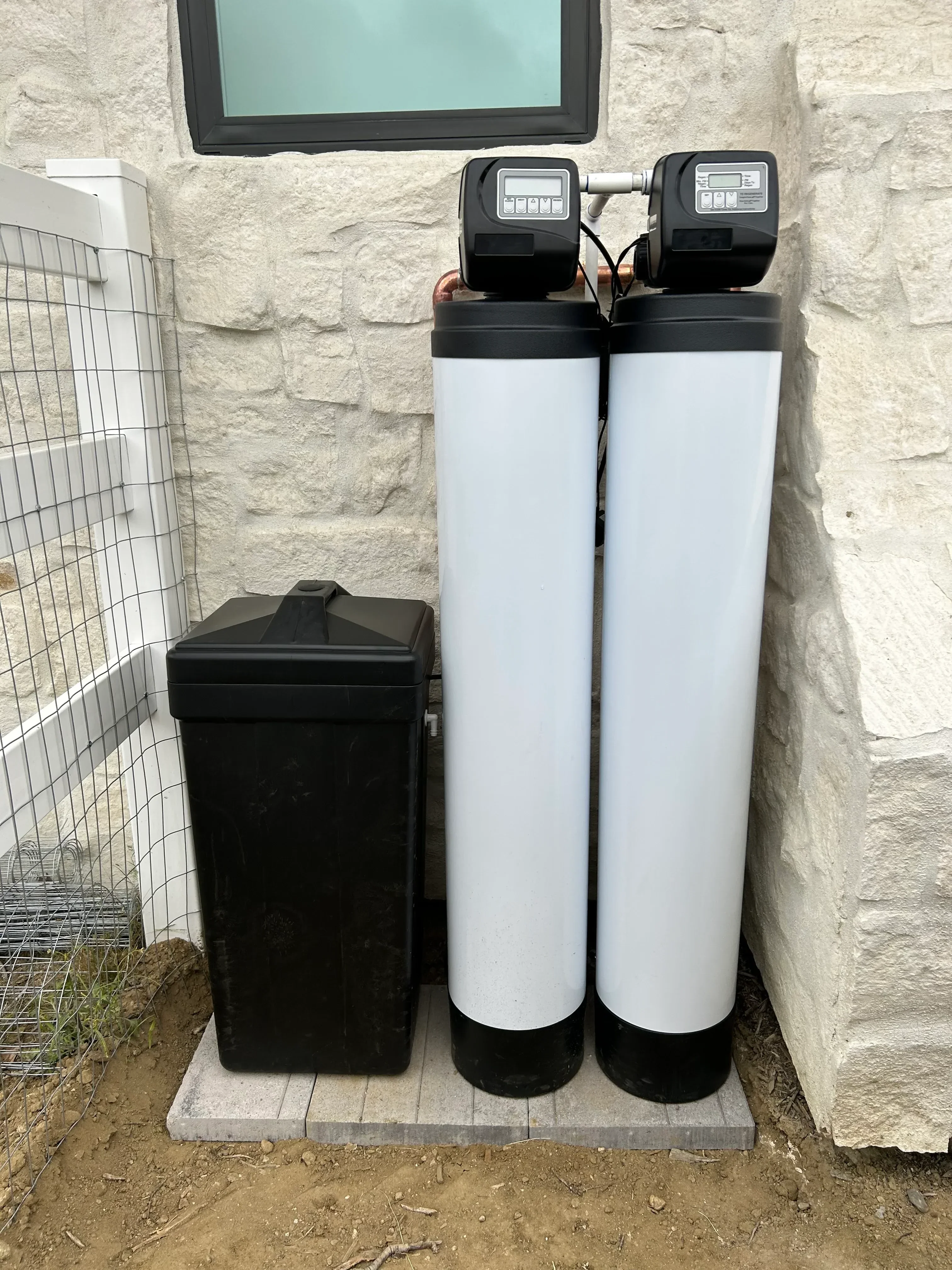 Dual white water softening tanks with digital control heads installed on concrete pad