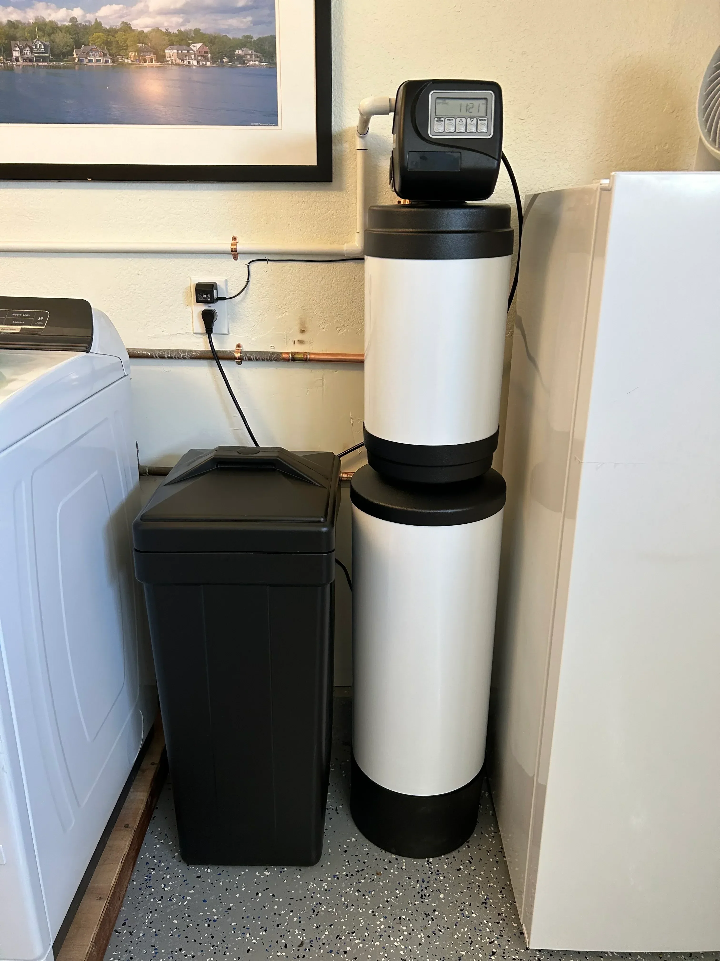 Installed whole-home water filtration system with cylindrical tank, digital controls, and water softener unit