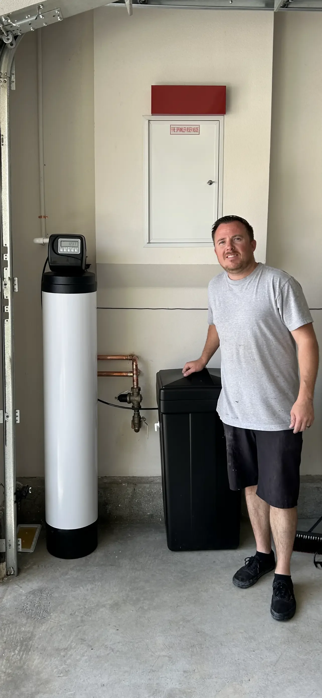 White water softener tank with digital meter and black resin tank installation with copper piping